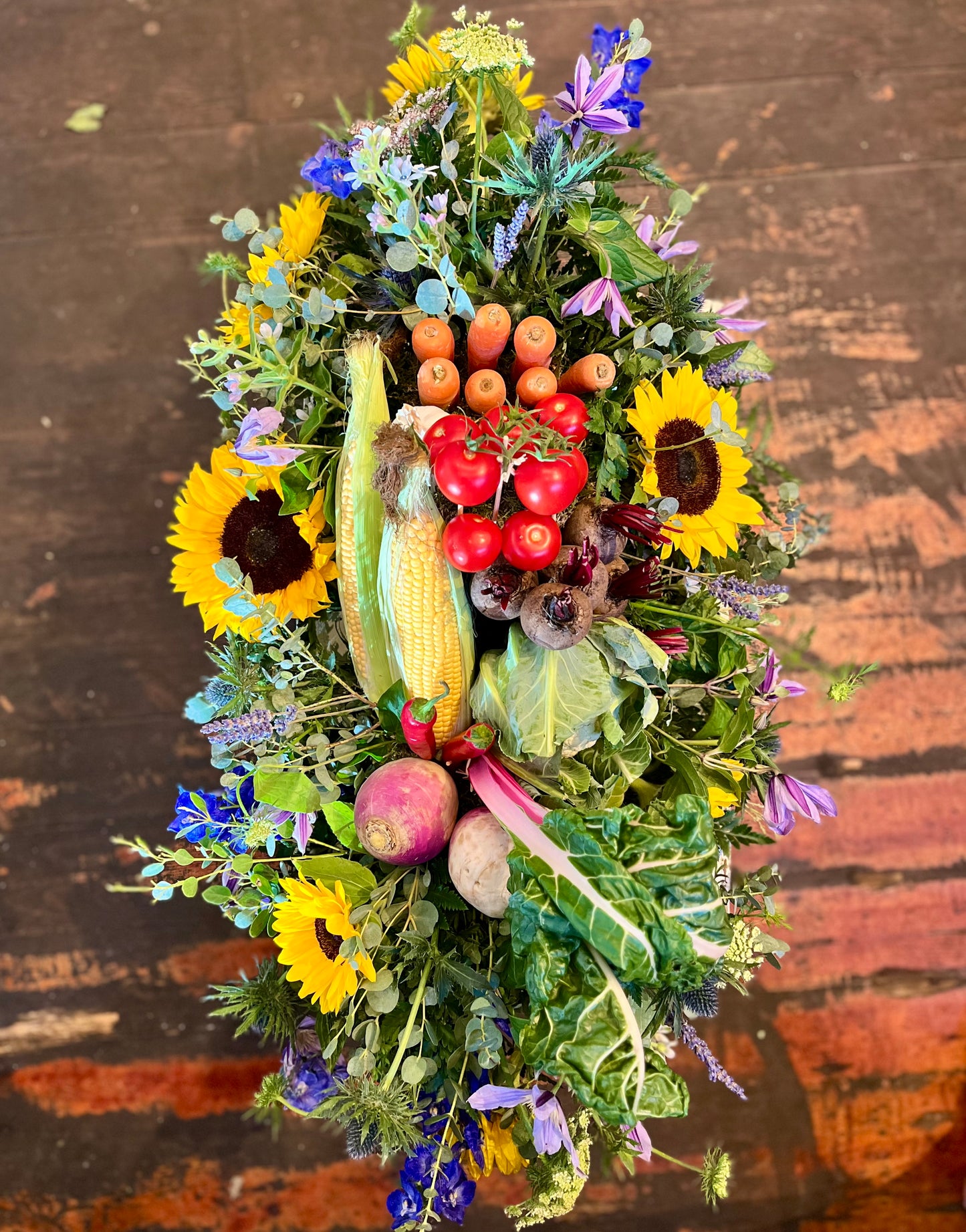 Decorative casket spray made of fruits, vegetables, and flowers on a wooden surface